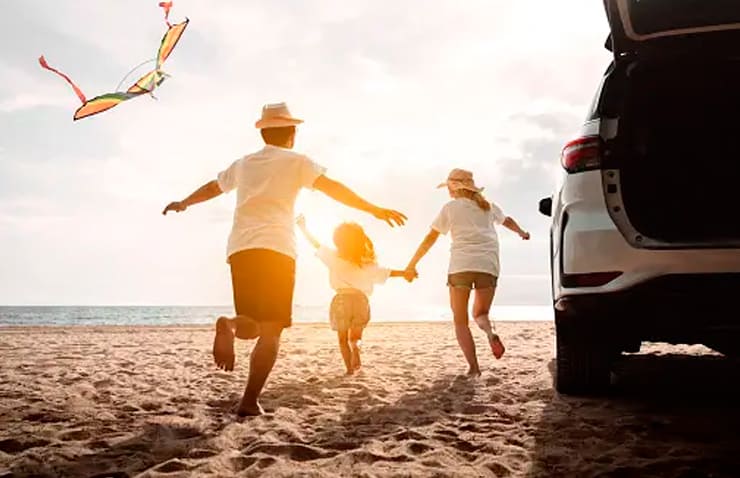 familia disfrutant de l'estiu a la platja amb el seu cotxe